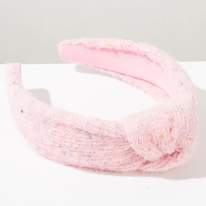 Dettaglio del cerchietto in peluche rosa con nodo e accenti intrecciati luminosi