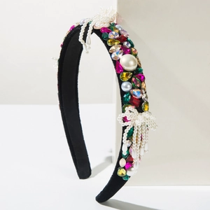 Detail of black velvet headband with colorful rhinestones and pearl bow accents