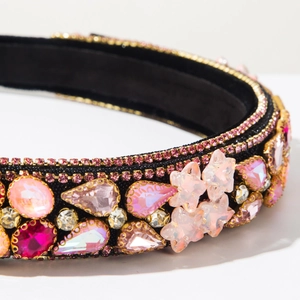 Detailed close-up of pink rhinestones and golden star accents on a baroque velvet headband