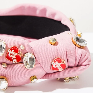 Detail of pink knot headband with rhinestones, pearls, and a Love heart charm