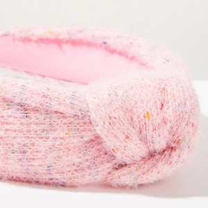 Dettaglio del cerchietto rosa con paillettes e nodo, texture in mohair morbido e maglia fine