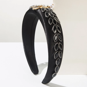 Detail of a black satin headband featuring marquee rhinestones and a gold bee jewel