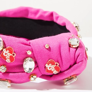 Macro detail of pink knotted headband with rhinestones and heart Love pendant charm