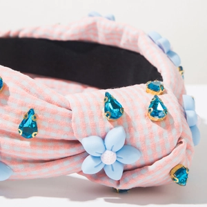 Détail d'un serre-tête en tissu rose à carreaux avec cristaux bleus et fleurs mates