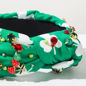 Detailed close-up of green clover printed knotted headband with strawberry and red gems