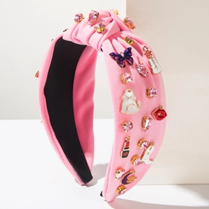Détail d'un serre-tête en tissu rose avec des cœurs en strass et breloques musicales
