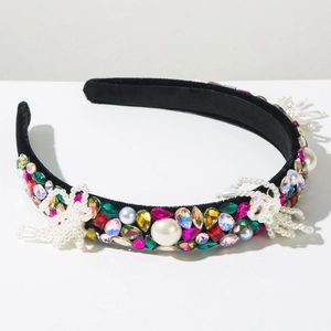 Detail of baroque headband with colorful rhinestones, pearls and bow on black velvet