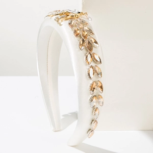 Detail of cream satin headband with golden feather and champagne crystal embellishments