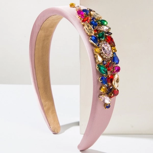 Pink satin padded headband decorated with colorful crystal rhinestones on a white stand