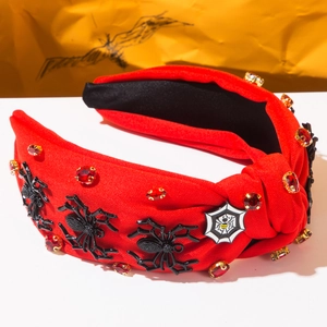 Détail d'un serre-tête d'Halloween rouge avec araignées noires, strass et badge de toile