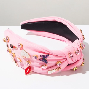 Détail d'un serre-tête rose avec strass et charms en forme de rouge à lèvres et papillon
