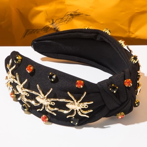 Détail macro du serre-tête gothique avec araignées dorées et strass oranges de fête