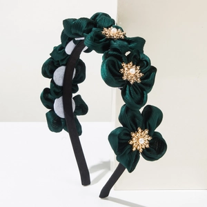 Detailed view of dark green silk flower headband with pearl and rhinestone center decoration