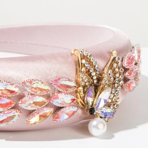 Detail of pink satin headband with golden butterfly wing and shimmering crystals