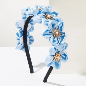 Close-up of light blue satin flowers with pearls and diamonds on a fabric headband