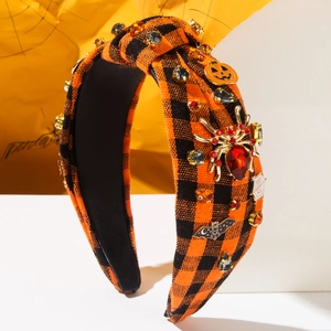 Detail of Halloween wide headband with spider and pumpkin charms on orange plaid fabric