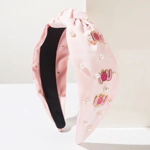 Detail of pink knotted headband with white pearls and gold letter decorative charms