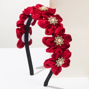 Detailed shot of red satin flower headband with gold stamens, pearls and crystals