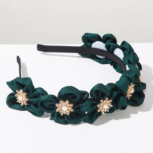 Detail of dark green fabric flower headband with pearl and rhinestone gold center