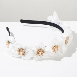Detail showing white fabric flowers with golden snowflake center and pearls on a headband