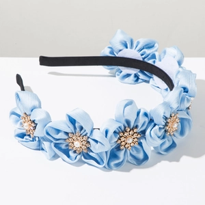 Detail view of light blue satin flowers with pearl centers on a slim black headband