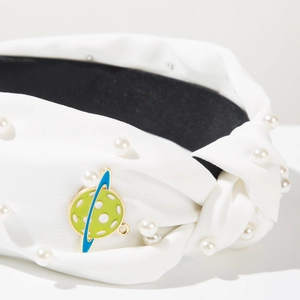 Detail of white knotted headband featuring faux pearls and blue planet charm drop oil