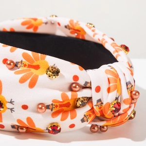 Détail d'un serre-tête noué en tissu avec imprimés de dinde et strass cousus à la main