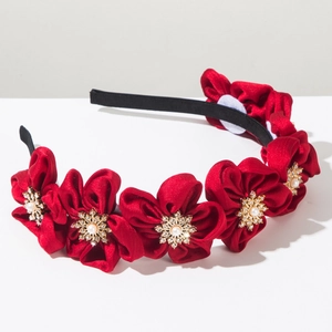 Detailed close-up of red fabric flowers with central white pearls and gold rhinestones