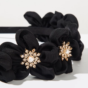 Detailed macro view of black fabric headband with pearl and rhinestone flower ornaments