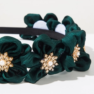 Detailed macro view of dark green satin floral headband with faux pearls and rhinestones