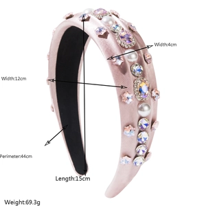Detail of pink satin headband with colorful rhinestones and pearls on white background