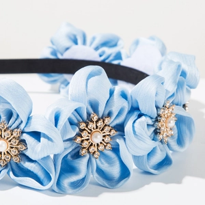 Detailed view of sky blue fabric floral headband with faux pearls and sparkling rhinestones