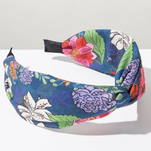 Dettaglio di un cerchietto annodato blu scuro con stampe floreali vivaci e colorate
