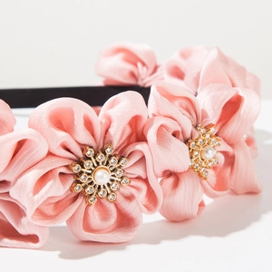 Close-up of pink satin floral headband with sparkling crystal and pearl centers