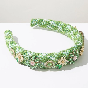Détail d'un serre-tête en tweed avec cristaux verts et marguerites en émail blanc