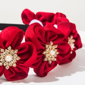 Macro detail of red satin floral headband with golden snowflake pearl center embellishment