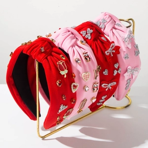 Detailed view of red and pink fabric knot headbands with rhinestones and heart charms