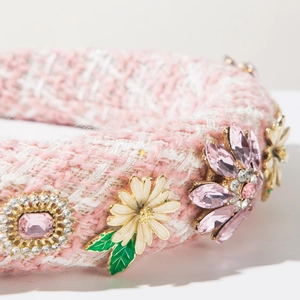 Détail d'un serre-tête en tweed rose et blanc avec fleurs en cristal et feuilles émaillées