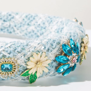 Détail d'un serre-tête en tweed bleu clair avec fleurs en cristal et marguerites blanches