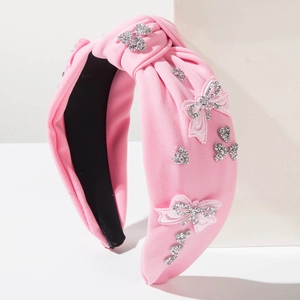 Close-up of pink fabric knot headband with sparkling rhinestone bows and heart patterns