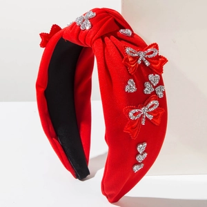Detail of red knotted headband featuring a satin bow and sparkling rhinestone heart accents