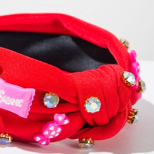Gros plan d'un serre-tête en tissu rouge avec bonbons en résine et strass brillants