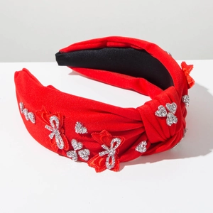 Detailed view of red fabric knotted headband with shiny rhinestones and ribbon bow decor