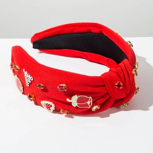 Detail of red knotted headband with rhinestones, enamel roses, and pearl heart
