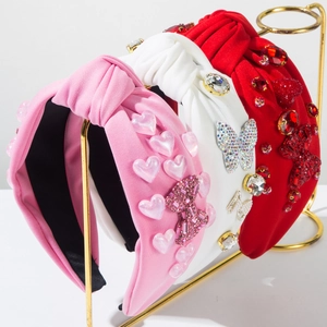 Detail of three wide knotted headbands featuring rhinestones and shiny heart-shaped charms