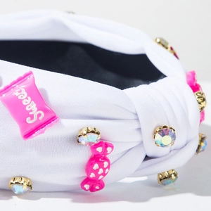 Gros plan de serre-tête noué blanc avec bonbons roses et strass irisés brillants