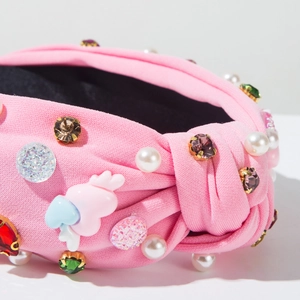 Detail of pink knotted headband featuring colorful rhinestones, pearls, and wings