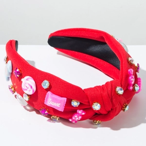 Détail d'un serre-tête noué rouge avec breloques bonbons, cœurs et strass étincelants