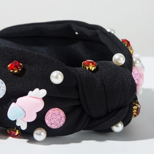 Detail of beaded headband with heart wing charms and pink faux pearls on black fabric