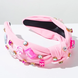 Détail macro d'un serre-tête en velours rose avec bonbons en résine et strass colorés